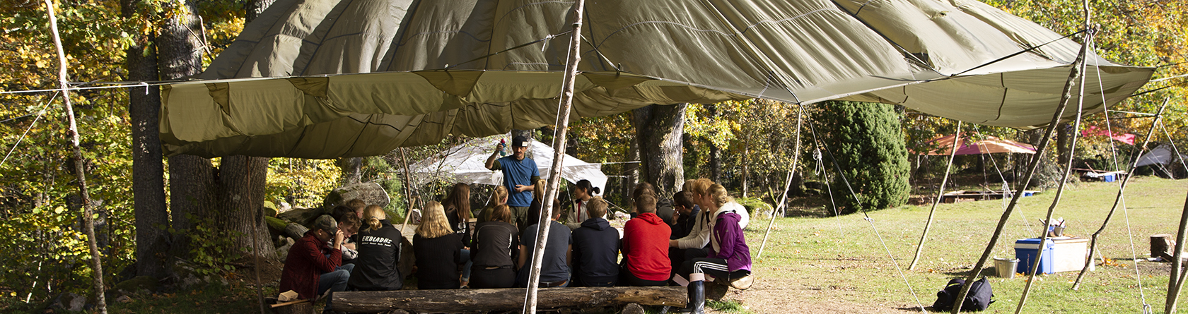Elever undervisas utomhus under en fallskärm.
