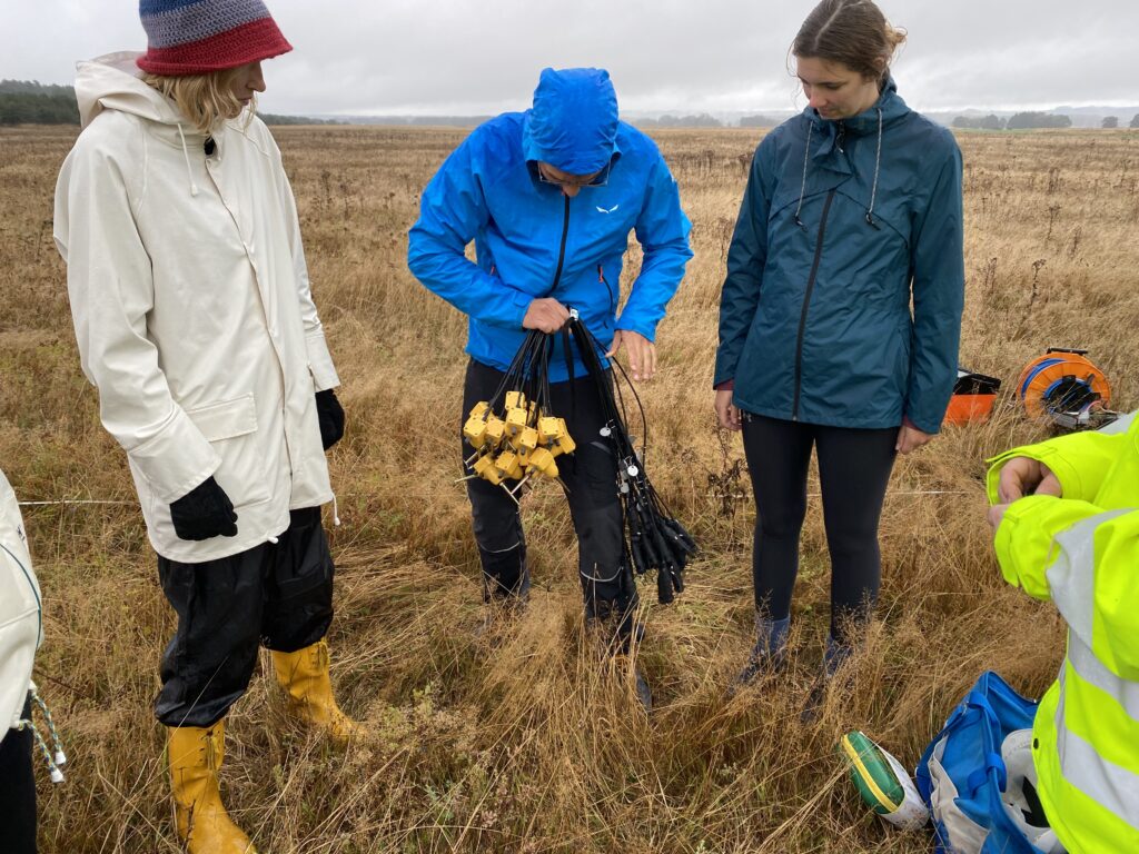 Tre personer jobbar med instrument för geofysikmätning