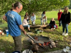 Besök av Hylte kommuns förskolepedagoger, augusti 2023. Juha Rankinen visar hur man lagar mat över öppen eld